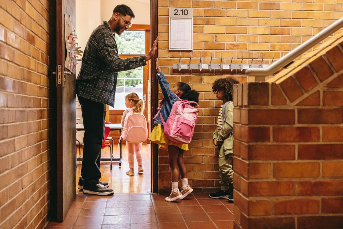 profesor chocando la mano a sus alumnos para darles la bienvenida